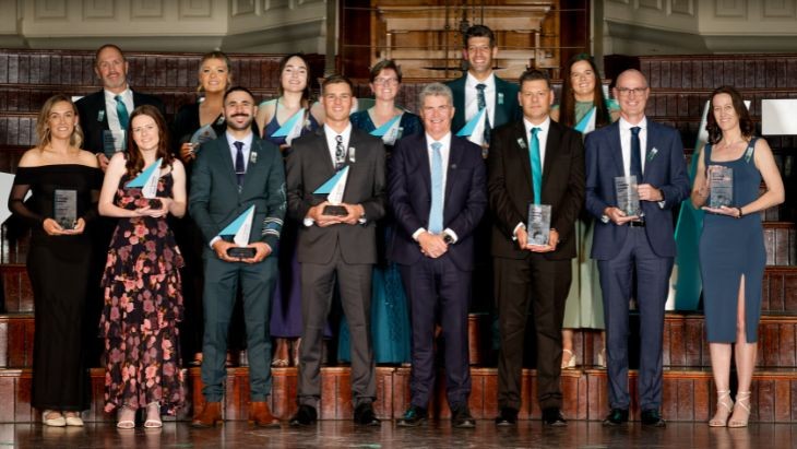 A group of people holding trophies standing in two rows.