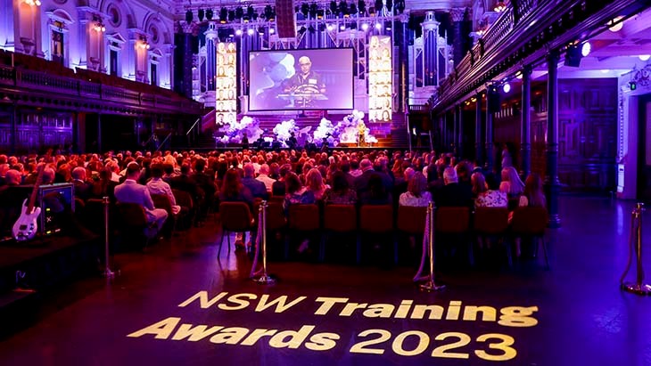 People seated in a hall with the words NSW Training Awards 2023 on the floor.