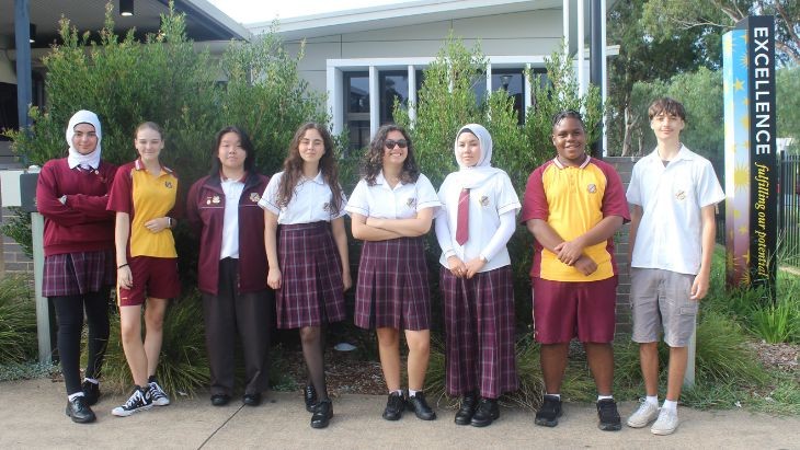 Students standing in a in front of a garden.