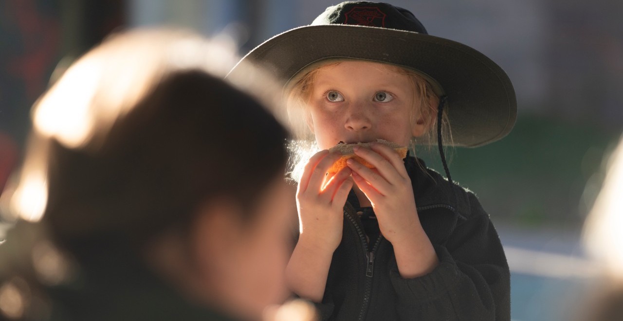 Young female student eating a sandwich outside in their school playground.
