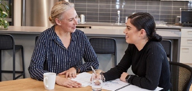 two women talking at a table in a kitchen