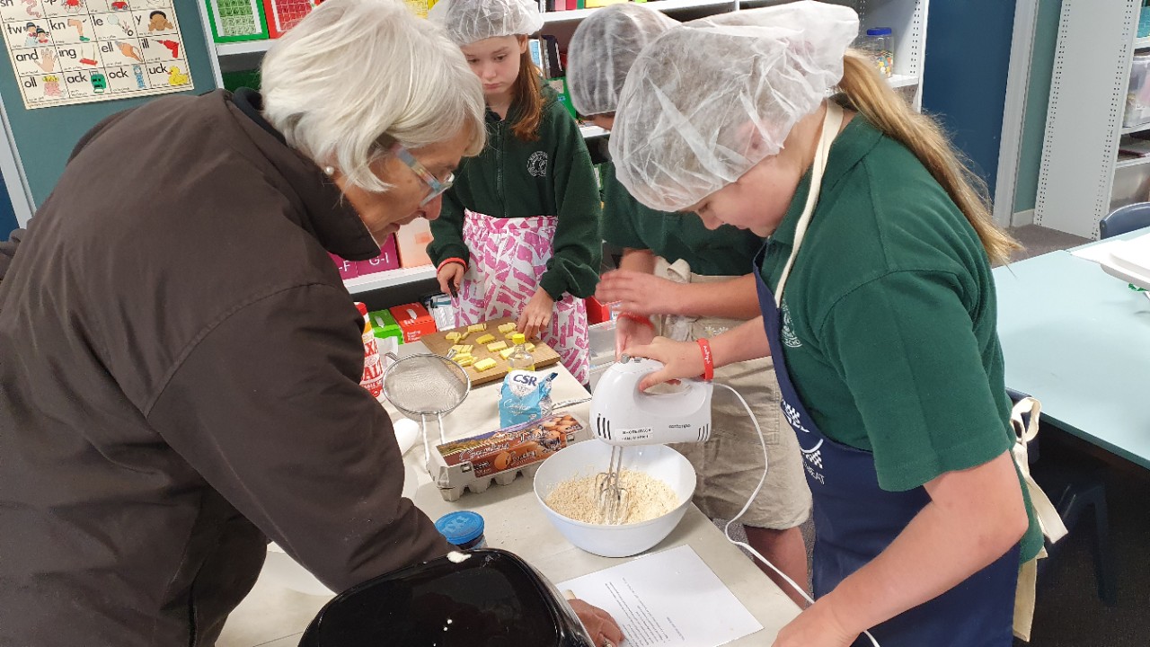 Teacher and three students preparing food and mixing ingredients in a bowl