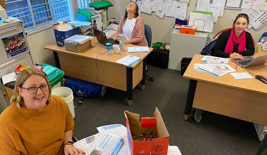 Three teachers sitting at various desks across an office.
