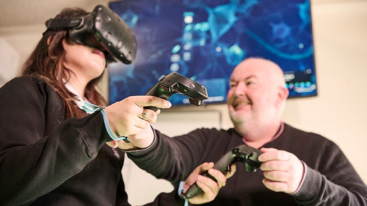 Young woman wearing virtual reality goggles with teacher.