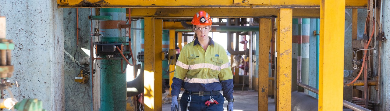 Female apprentice walking towards the camera on a construction site. 