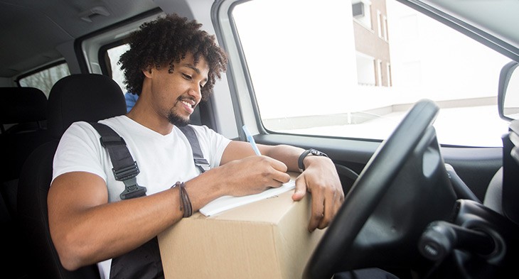 Male in car filling out form on parcel.