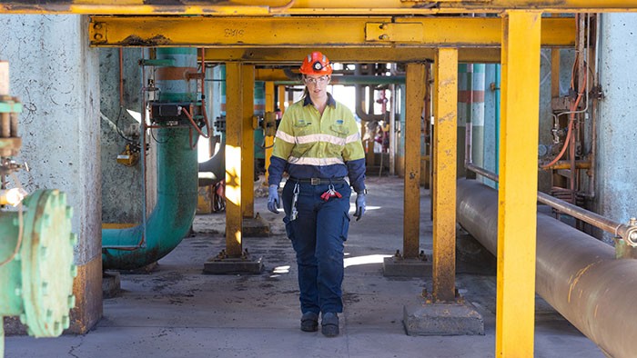 Female apprentice construction worker wearing PPE walking