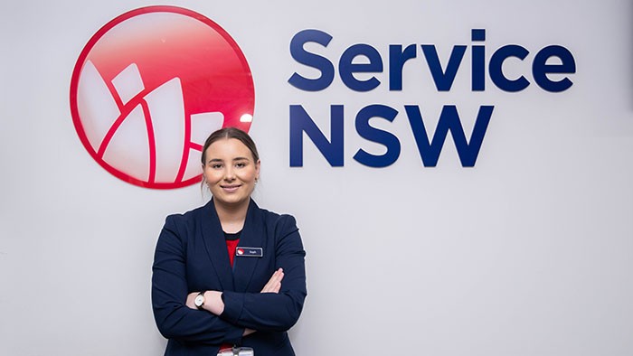 Smiling VET graduate Sophia stands in front of Service NSW building