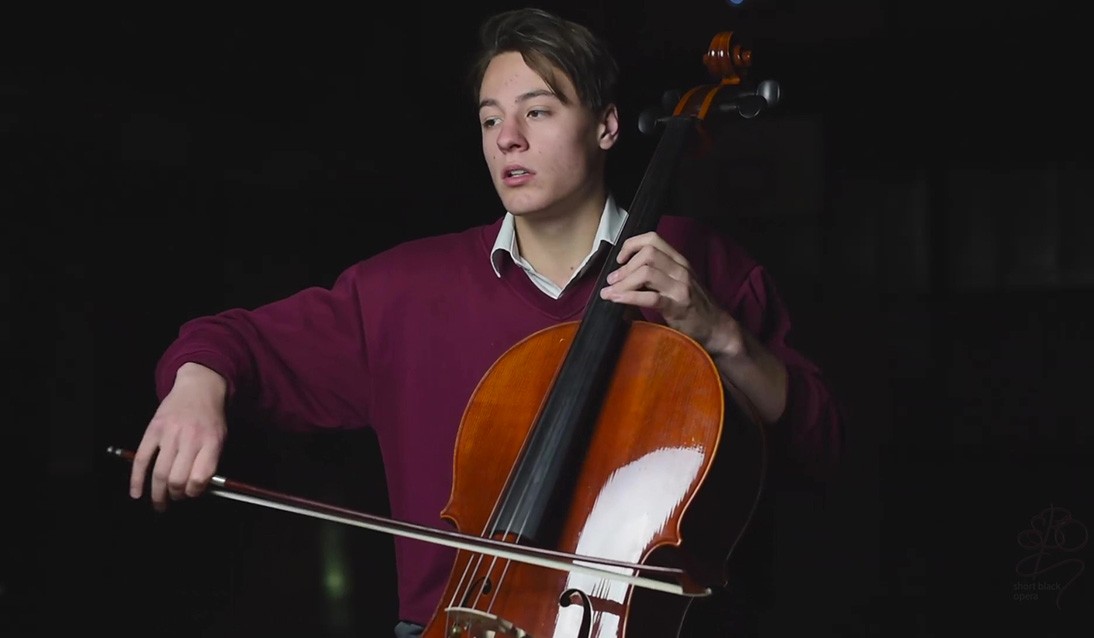 Male student wears maroon jumper and plays the cello.