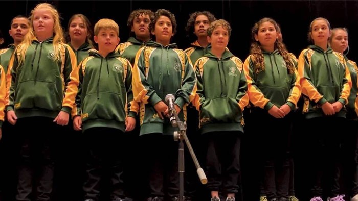 group of students wearing green jumpers with a microphone in front of them