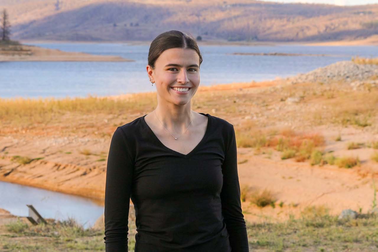 Young woman in black shirt smiling with garden beds behind 