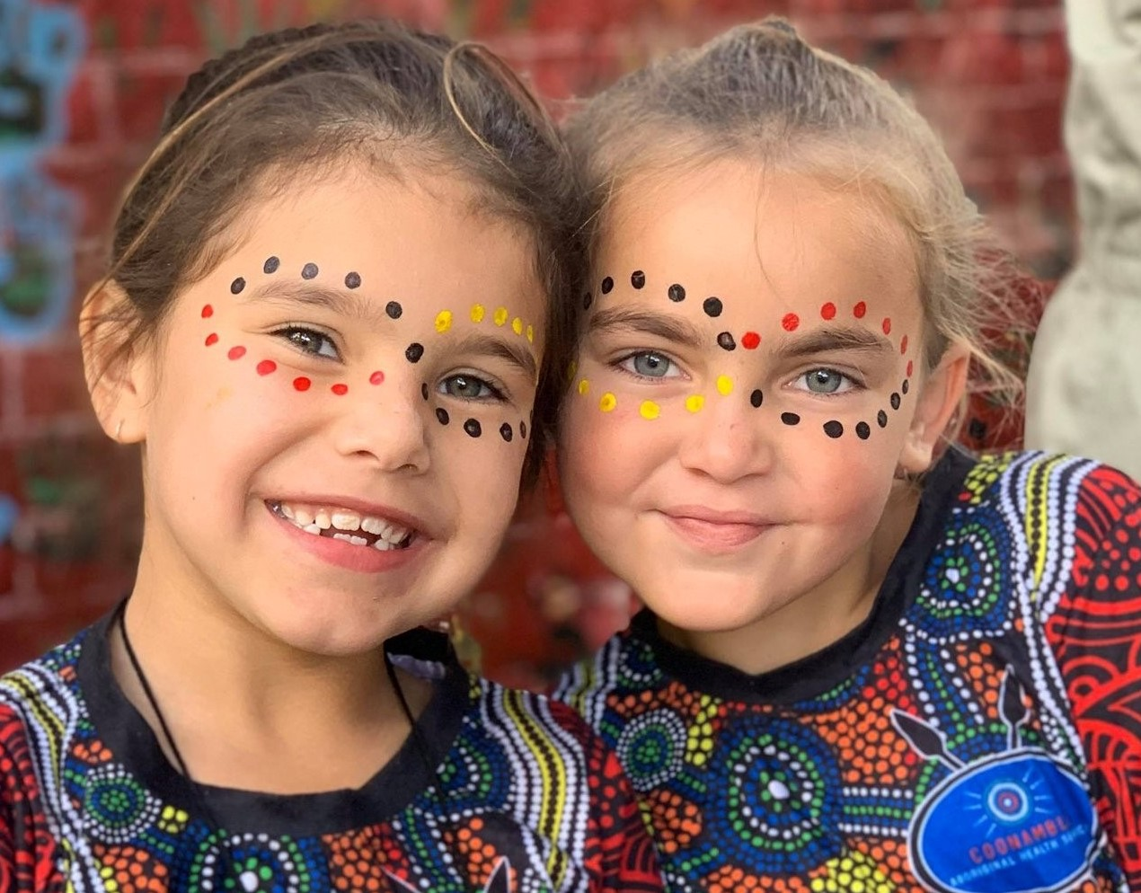 Two female students with face paint smiling at camera