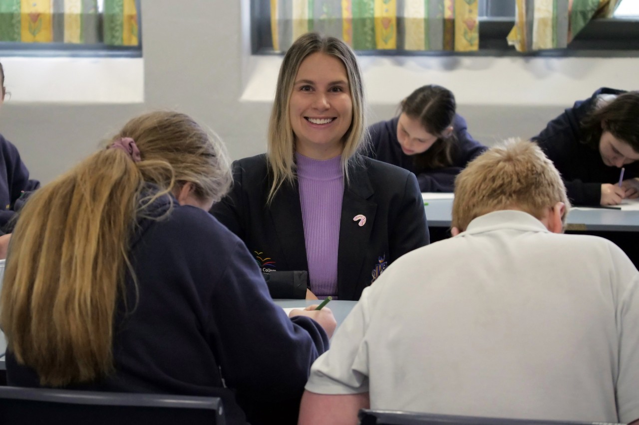 Female teacher in classroom smiling at camera