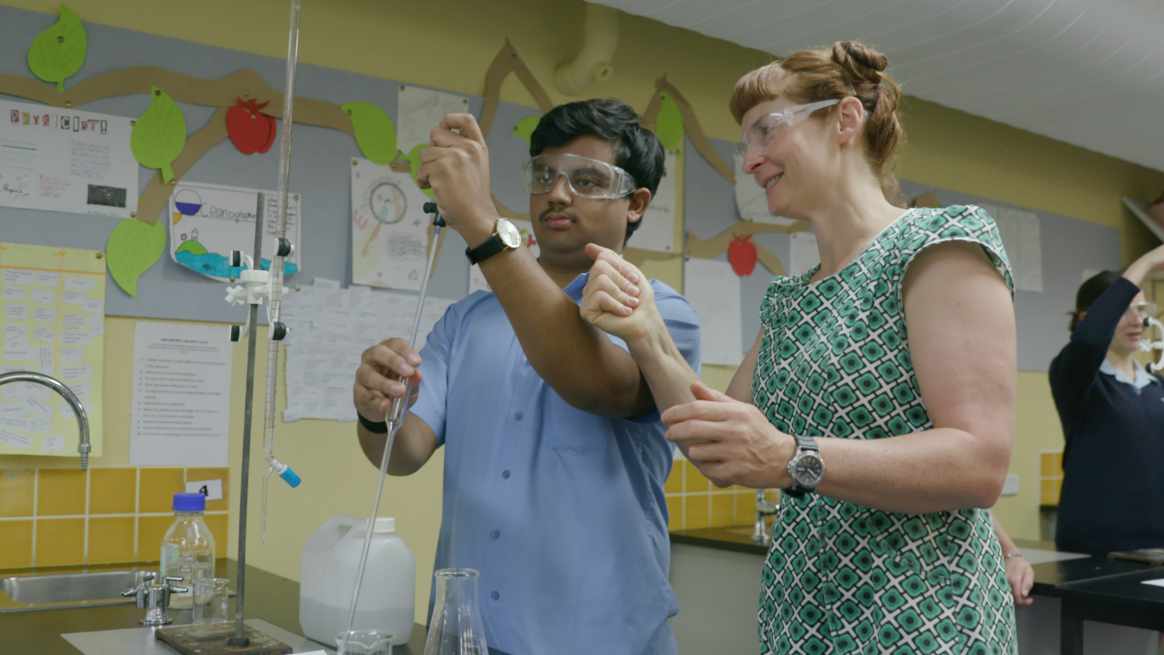 Female science teacher doing an experiment with a male student