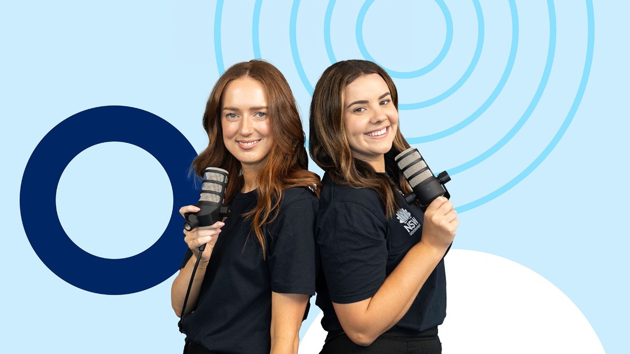 Two females holding microphones smiling at the camera