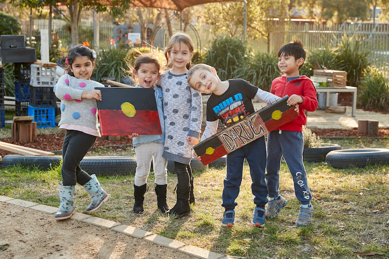 Primary_school_students_standing_outside_holding_aboriginal_indigenous_flag