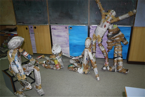 Paper people sculptures in the classroom. 5 sculptures showing people forms in various positions some seated some standing..