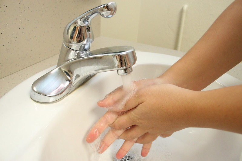 Child washing hands in a basin.
