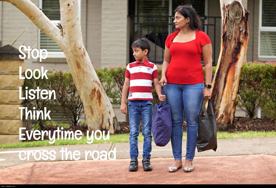 Image of woman and child holding bags and looking to their right before crossing the road