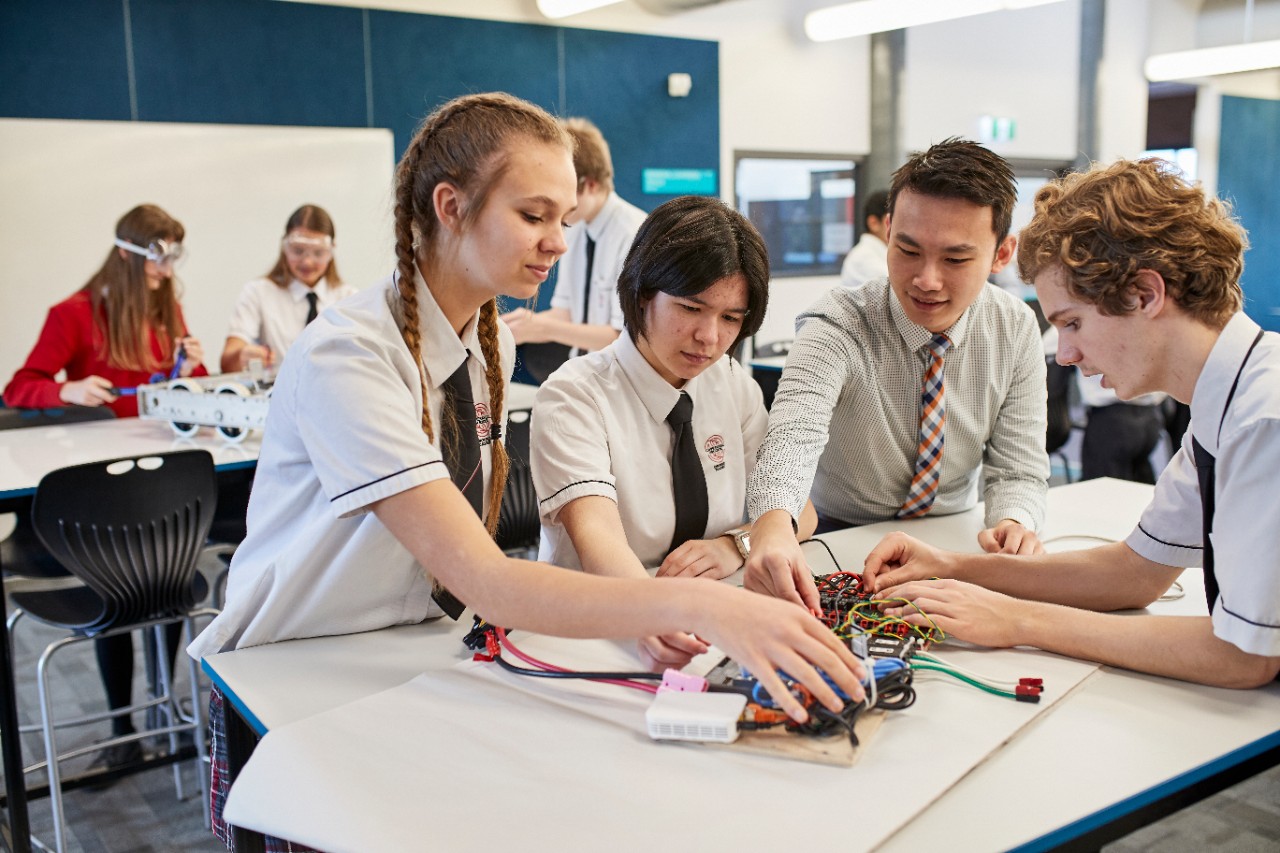 Three students and their teacher work on a STEM activity