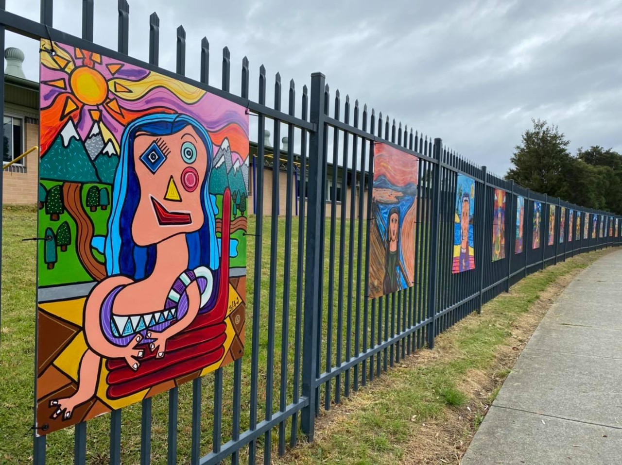 Large painted portraits mounted on a school fence.
