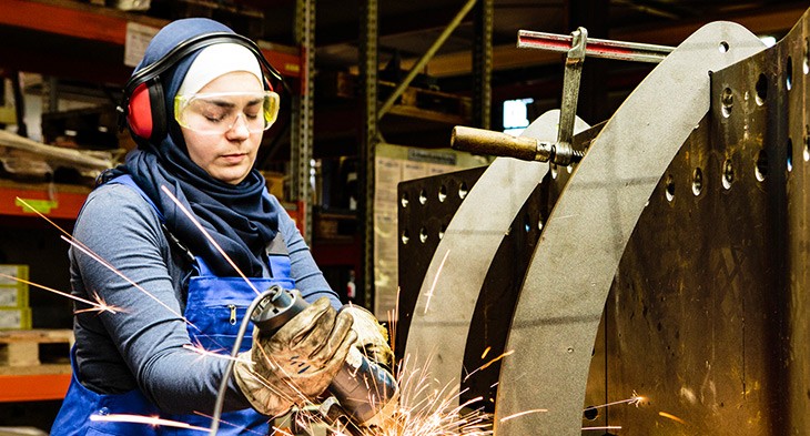 Female in a factory working with an angle grinder.