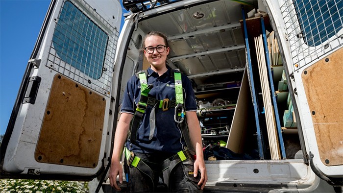 Female apprentice electrician in back of work van