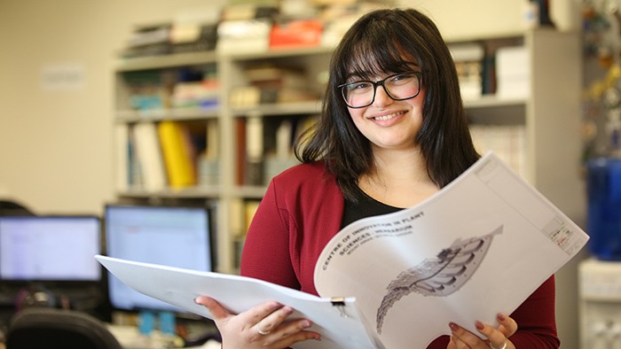 Young woman in office smiling looking through plans