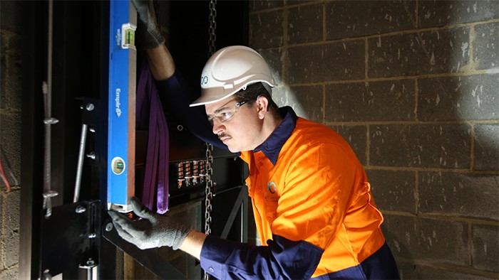 Male VET construction apprentice checking level