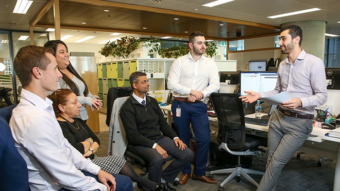 A group of adults having a stand-up meeting in an office