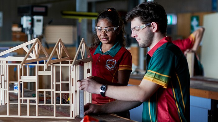 Two students work on a model of a building